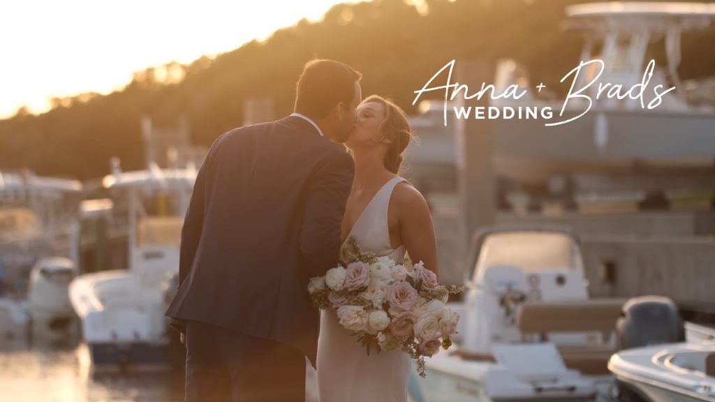 bride and groom kissing in front of boats at a marina